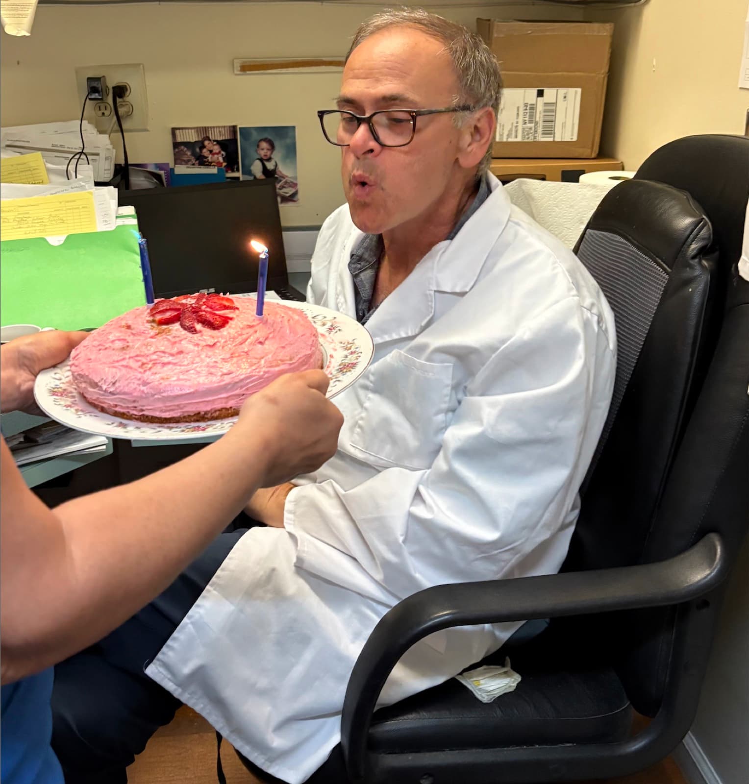 Dr. Goldfarb blowing out candles on a birthday cake at the office