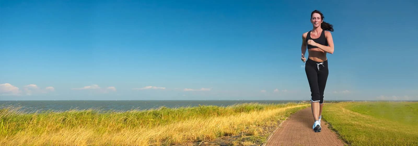 A woman jogging comfortably on a seaside path